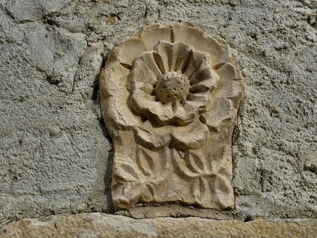Bâtiment du logis. Elévation ouest, premier niveau. Porte du logis, sculpture de rose en bas relief.
