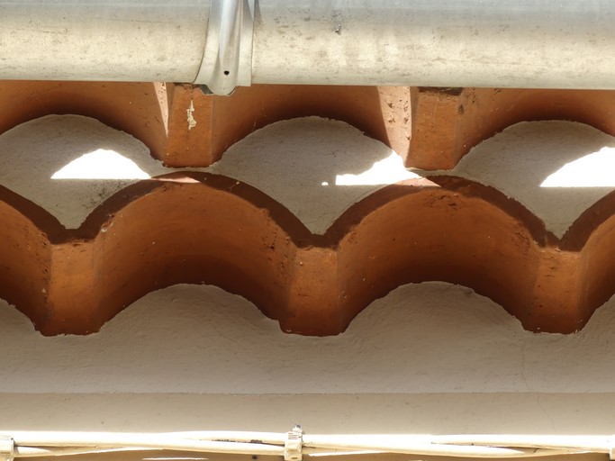 Avant-toit constitué de deux rangs de génoise peints en blanc et rouge. Maison située rue de la Draille au bourg de Ribiers (parcelle 1998 E2 768).