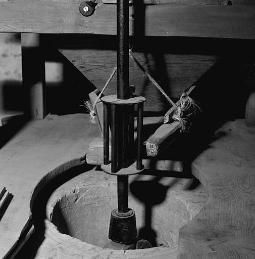 L'entre-muie (entonnoir en bois) et le rout (plate-forme vibrante qui assure une distribution régulière du grain).