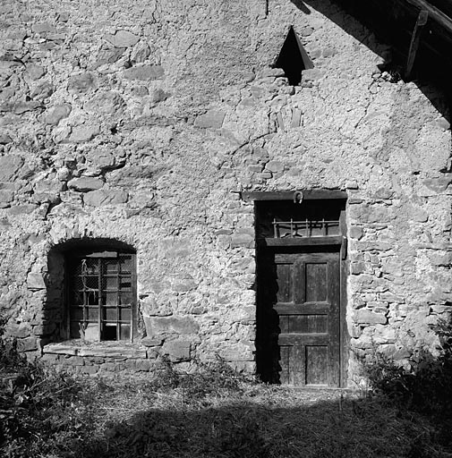 La porte du logis. Noter l'imposte vitrée, l'oculus triangulaire et le fer à cheval cloué sur le linteau.