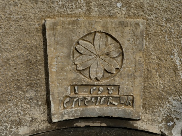 Bâtiment du logis. Elévation ouest, premier niveau. Porte du logis : cartouche sculpté et date en réserve (1598) accompagnée d'une inscription (ES. REINIER).
