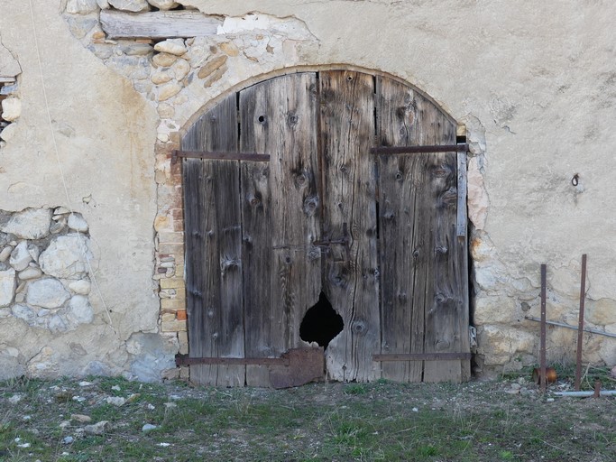 Porte de remise-étable avec encadrement en arc segmentaire en brique pleine. Ferme au hameau de Saint-Aubert (Ribiers).