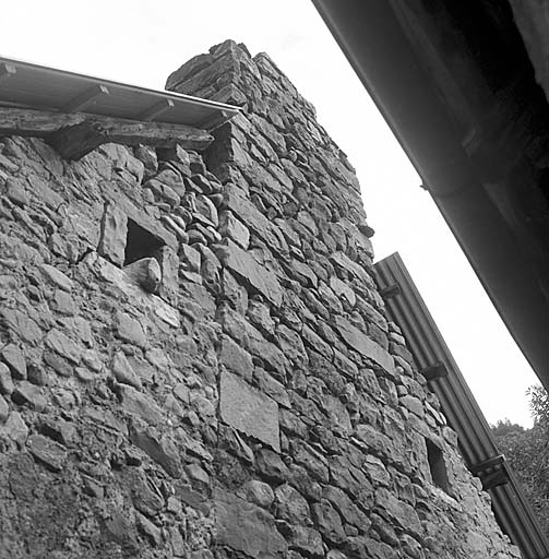 Noter les deux fenêtres carrées qui encadrent la cheminée construite indépendamment du mur.