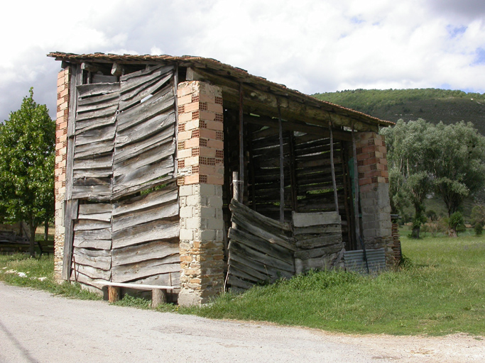 Clumanc. Toueste. Hangar à clôture de planches et piliers en maçonnerie mixte (grès, parpaing artisanal, brique creuse).