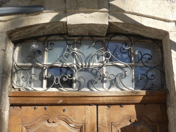 Porte de logis avec châssis de tympan équipée d'une grille en ferronnerie. Maison située place de la Fontaine à Ribiers (parcelle 1998 E2 642).