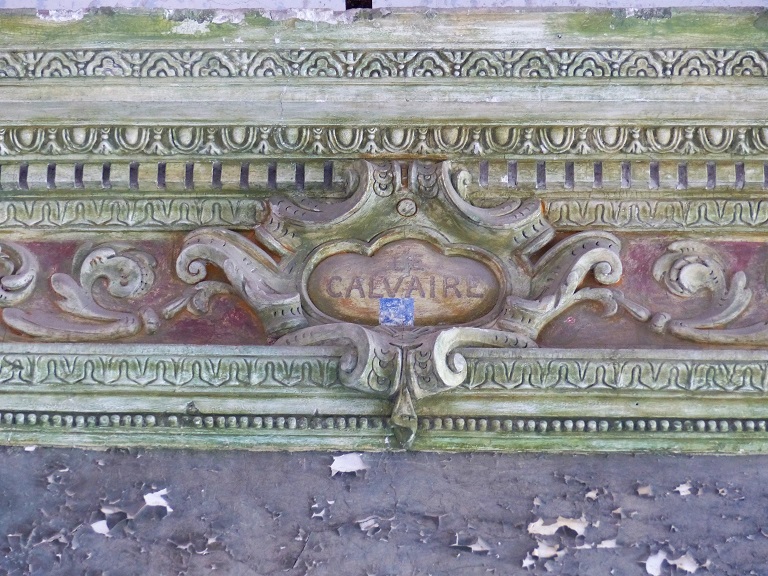 Deuxième travée (nef). Mur nord, détail du cartouche au centre de la corniche portant l'inscription peinte "LE CALVAIRE".