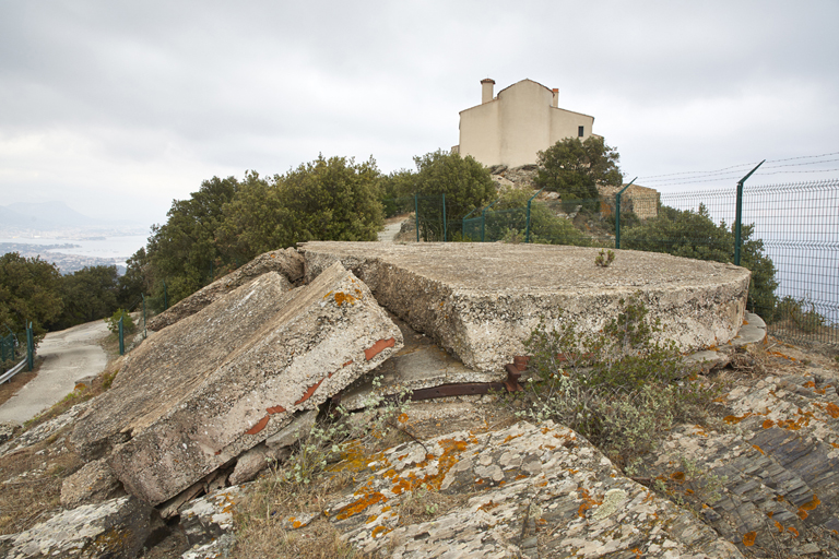 Ruines de la dalle de couvrement du probable poste de conduite de tir; à l'arrière-plan, la chapelle.