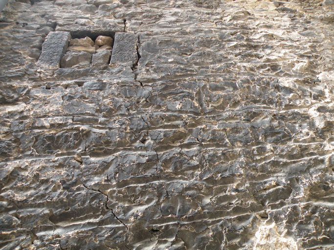 Enduit rustique avec faux appareil grossier gravé ; baie murée. Importantes traces de suie.