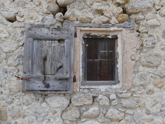 Fenêtre de logis saisonnier, occultée par un contrevent à cadre. Bâtiment au quartier du Rata (Ribiers).