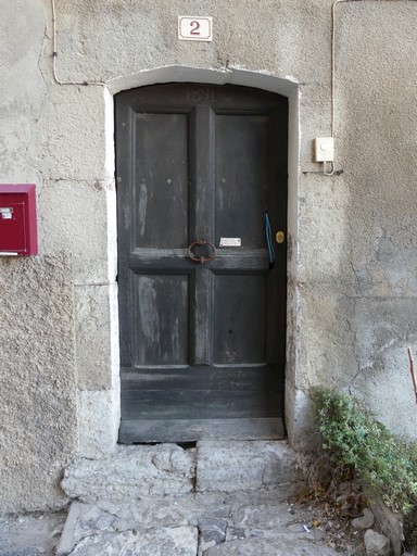 Porte de logis avec encadrement en arc segmentaire ; menuiserie à panneaux moulurés portant la date peinte 1891. Maison située descente du Canal au bourg de Ribiers (parcelle 1998 E2 764).