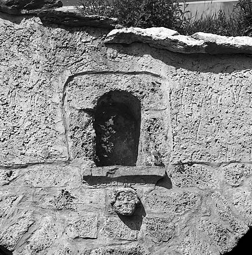 Niche et masque dans le mur de la fontaine. Inscription : S M 1853.