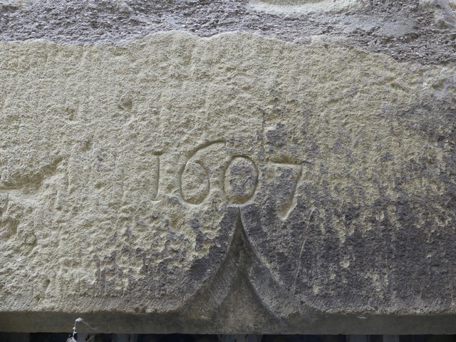 Elévation ouest, premier niveau. Ancienne porte du logis, linteau chanfreiné à double accolade avec date gravée (1607).