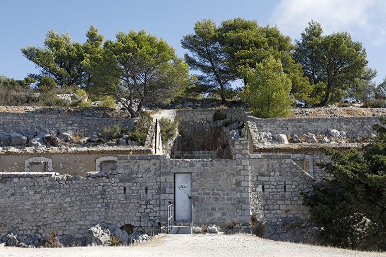 front de gorge de l'enceinte : détail de la porte de l'ouvrage avec créneaux, vue de l'extérieur, à l'arrière plan la cour entre les casernements