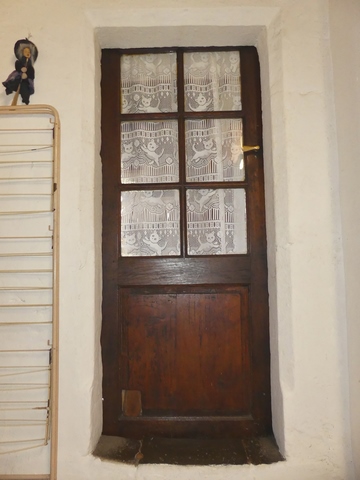 Bâtiment du logis. Rez-de-chaussée surélevé, cuisine. Mur est, porte de communication avec la chambre est : encadrement chanfreinée avec congés en biais.