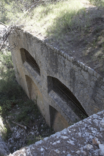 Premier flanc, vue plongeante sur façade revêtue du flanc actif, avec fenêtres défensives et créneaux de pied.