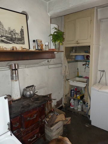 Rez-de-chaussée surélevé, cuisine. Mur nord, cheminée et pile d'évier surmontée d'un placard mural.