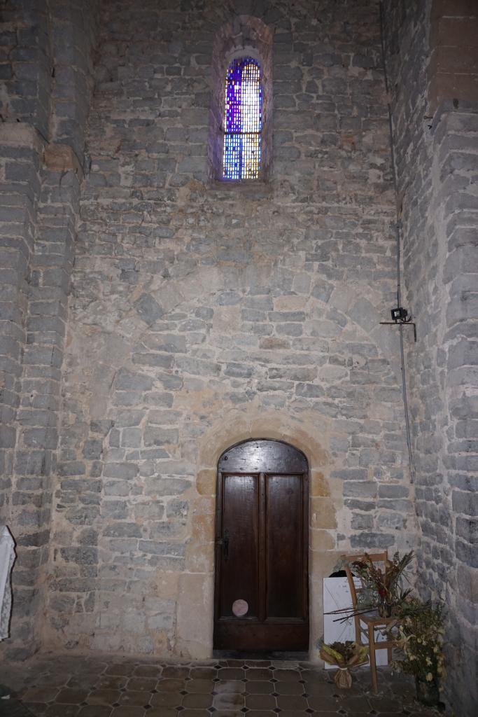 Accès à la sacristie : arc en plein cintre disparaissant derrière un pilier, baie ménagée dans le comblement.
