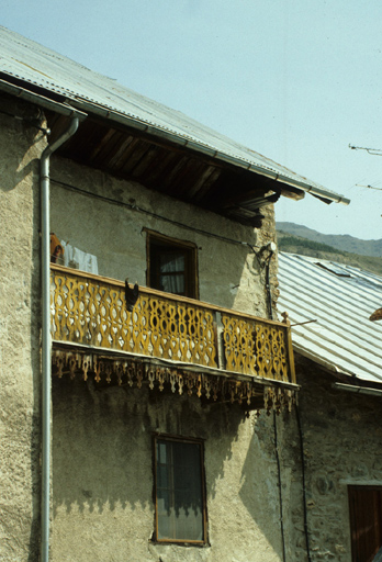 Le Casset. Parcelle 1177. Façade sud. Au premier étage, un grand balcon en bois à balustres plats découpés et à lambrequin.