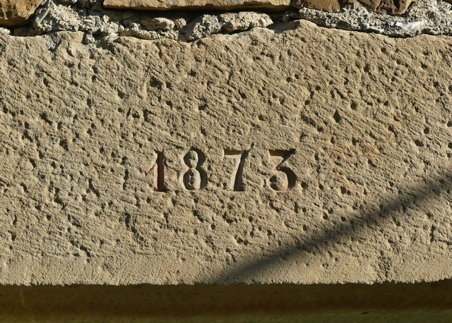 Bâtiment principal. Elévation sud, premier niveau. Porte de la meunerie, date gravée « 1873 ».