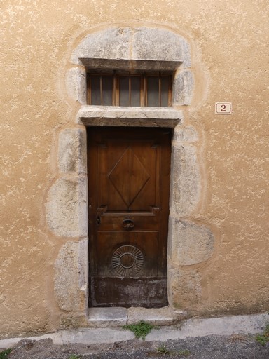 Porte de logis avec encadrement chanfreiné surmonté d'un jour sur traverse ; menuiserie moulurée et sculptée. Maison située rue Charlotte au bourg de Ribiers (parcelle 1998 E2 619).