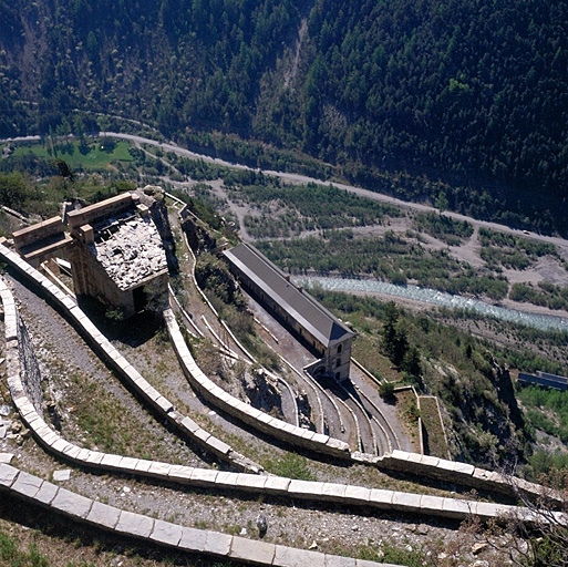 Fort supérieur. Vue plongeante des rampes descendant du fort moyen. A gauche porte d'entrée arrière. Au centre et en contrebas, le bâtiment B (pavillon d'officiers). Au fond, vallée de l'Ubaye et pied des pentes de la Silve.