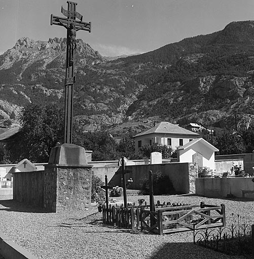 La croix en métal (mission 1935) se dresse au centre du cimetière, face à l'entrée.