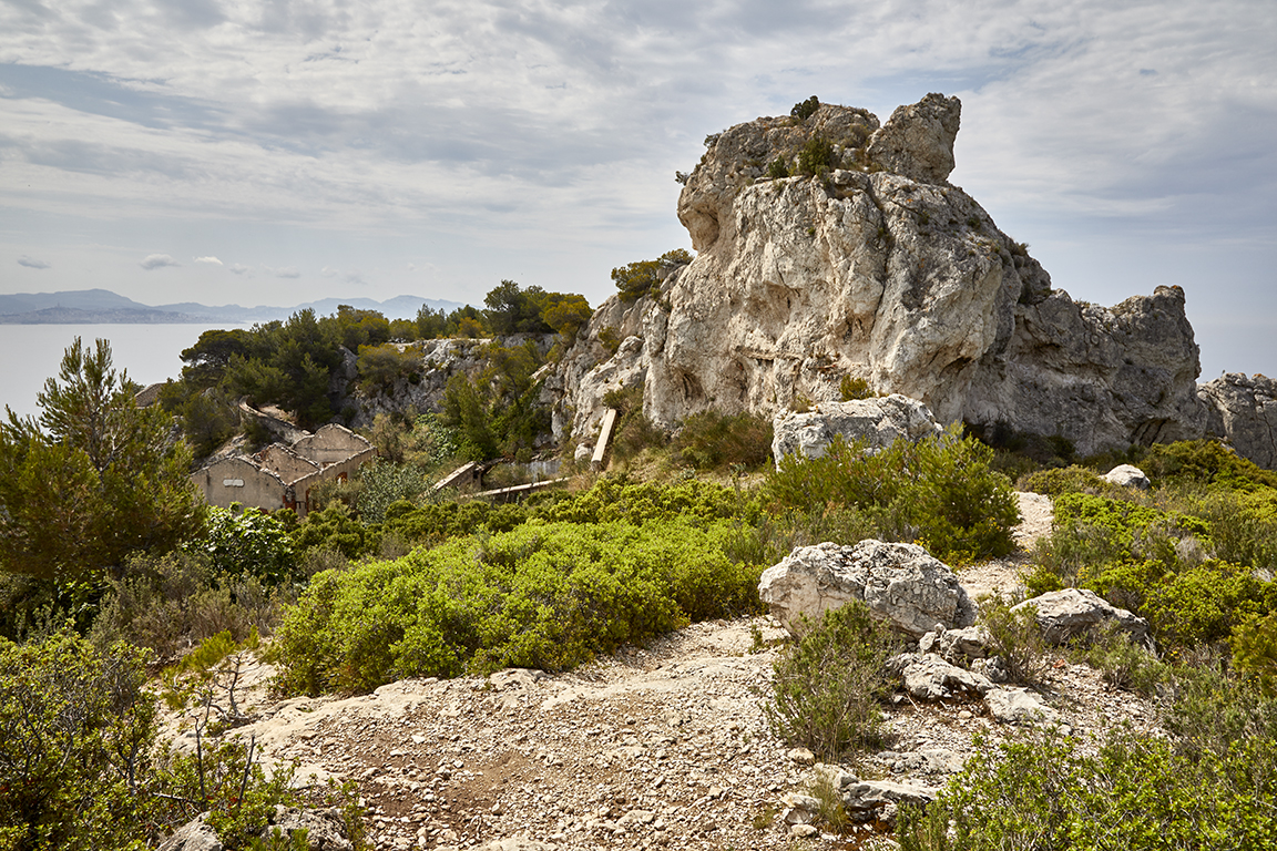 Vue générale du site de la baterie vu du bord-ouest, bâtiments militaires de la cour d'entrée dominés par l'arête rocheuse.