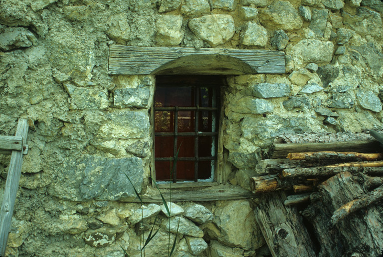 La fenêtre du chambron. Noter le linteau en bois délardé en arc et la grille en fer forgé.