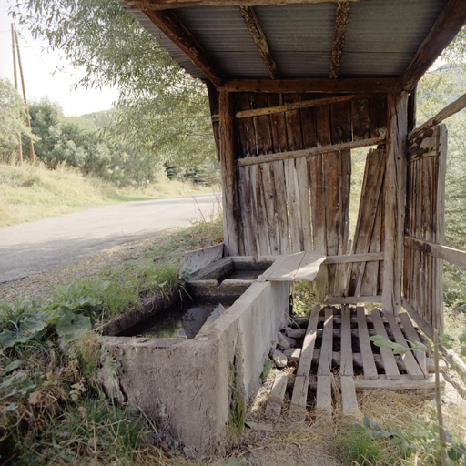 Allos. Fontaine-lavoir au Villars Bas. On remarque la présence de la planchette de lavage en bois, le caillebottis servant à égaliser le sol irrégulier ainsi que l'abri couvert de tôle et initialement clos sur trois côtés avec des planches de mélèze.  