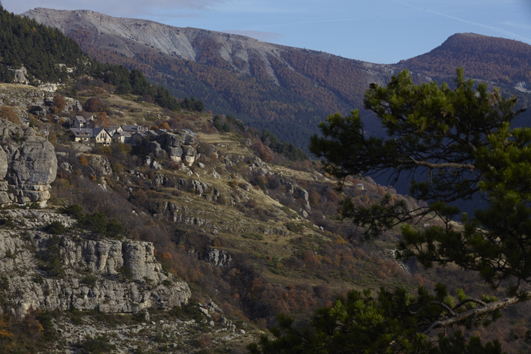 Vue de situation de l'écart de Peyresq dans son contexte paysager depuis la route départementale 32 (on devine les restes des terrasses de cultures en contrebas de l'ancien village).