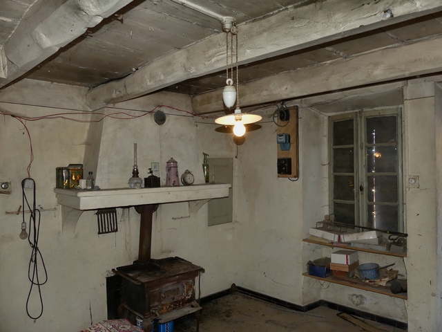 Rez-de-chaussée surélevé, cuisine. Angle sud-ouest : cheminée et petit placard-niche, fenêtre.