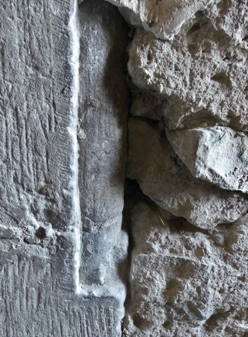 Rez-de-chaussée surélevé, escalier. Mur nord, porte murée. Détail d'un piédroit décoré d'un tore.