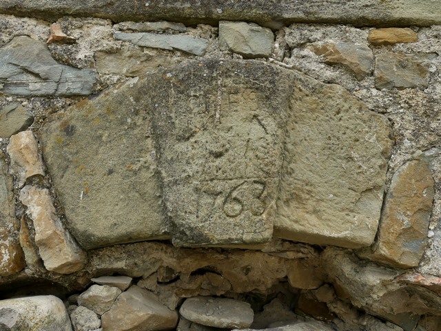 Claveau remployé avec date (1763) et initiales gravées, bâtiment du logis d'une ferme au quartier du Buisson.