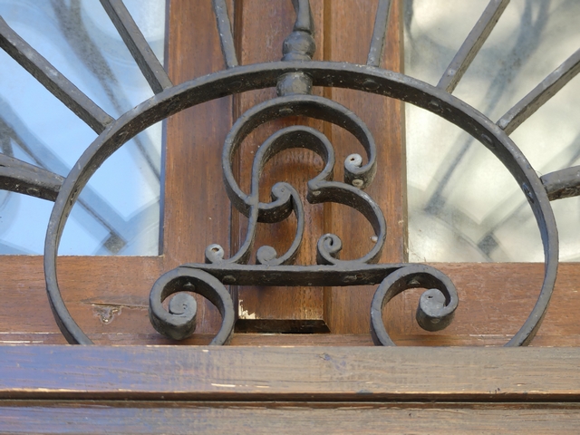 Elévation nord, deuxième niveau. Porte du logis, imposte. Grille en ferronnerie : Initiales G et B entrelacées [image retournée en miroir].
