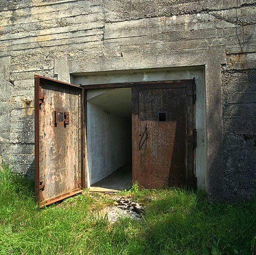 Ouvrage d'artillerie dit batterie Peluna : porte d'accès aux emplacements de tir à barbette des obusiers de 100 avec vantaux métalliques en place.