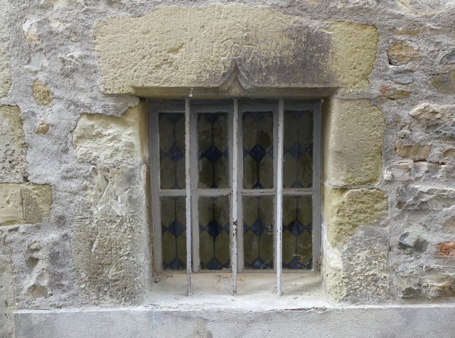 Elévation ouest, premier niveau. Ancienne porte du logis, linteau chanfreiné à double accolade avec date gravée (1607).