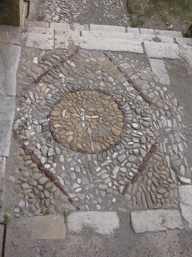 Sausses. Château. Jardin occidental. Pavement en mosaïque de cailloux devant la porte du château.