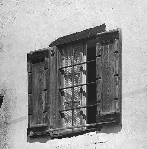 La fenêtre ouest du premier étage. Le dormant est au nu de la façade. Les volets comportent des encoches destinées au passage des barreaux.
