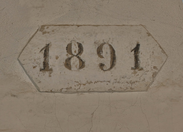 Bâtiment principal. Pignon est, premier niveau. Date gravée « 1891 » sur le linteau de la porte.