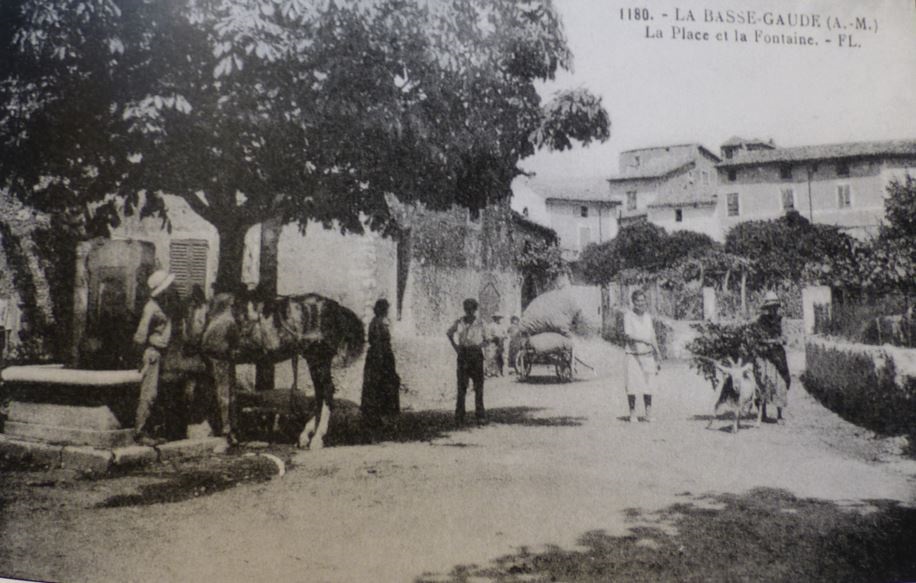 1180. – LA BASSE-GAUDE (A.-M.) / La Place et la Fontaine. – FL. [Vue prise du sud. En arrière plan au centre, la façade sud de la ferme surélevée].