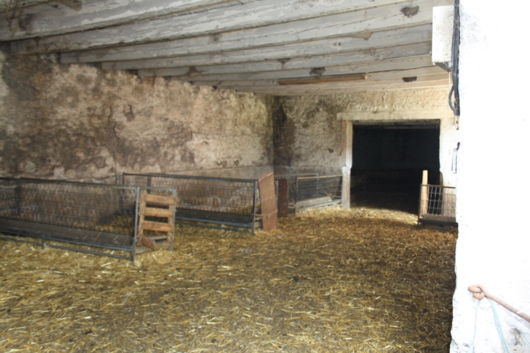 Vue intérieure de la bergerie au rez-de-chaussée du bâtiment 1, prolongée par celle du bâtiment 2 (a) à l'est.