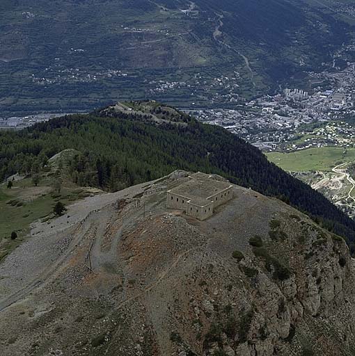 Vue aérienne d'ensemble : au loin la ville de Briançon, au 2e plan le fort de la Croix de Bretagne et au 1er plan le blockhaus.