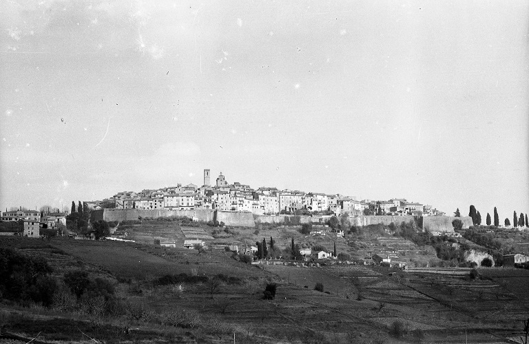 [Vue de situation du village de Saint-Paul-de-Vence prise de l'ouest, entouré de parcelles cultivées, milieu du 20e siècle].