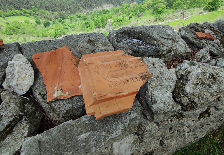 Enclos-cour. Mur sud, détail des fragments de tuiles plates mécaniques portant la marque du fabricant : "Arnaud Etienne" à "Marseille".  