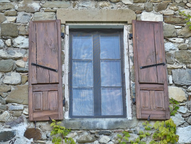 Bâtiment du logis, partie est. Elévation sud, second niveau. Fenêtre équipée de contrevent à planches croisées avec soubassement à panneaux moulurés.