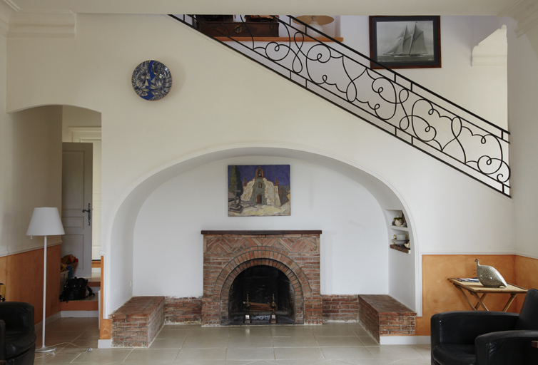 Living-room. Cheminée et banquettes en brique. Escalier d'accès à l'étage.