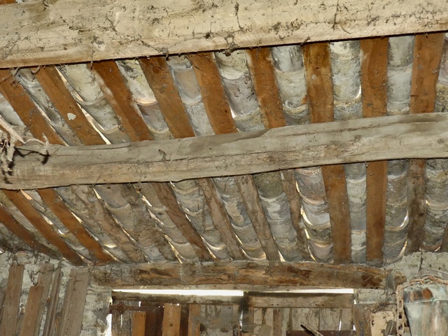 Charpente à pannes et couverture en tuiles creuses sur chevrons en quartons, entrepôt agricole au bourg.
