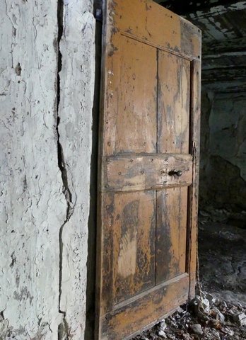 Bâtiment principal. Rez-de-chaussée surélevé, cuisine. Mur nord, porte de la chambre nord-ouest.