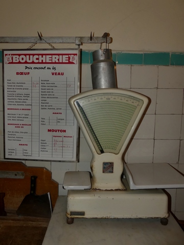 Rez-de-chaussée surélevé, boucherie. Balance et affiche des tarifs.