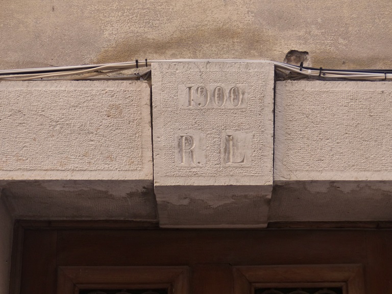 Elévation ouest, premier niveau. Porte du logis, détail de la clé portant l'inscription 1900 R.L. 